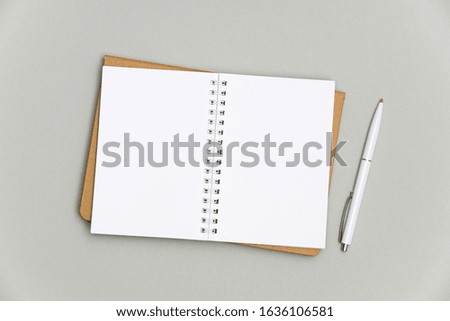 Blank spiral notepad with white pen isolated on gray background. High resolution image