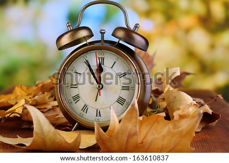 Old clock on autumn leaves on wooden table on natural background Royalty-Free Stock Photo #163610837