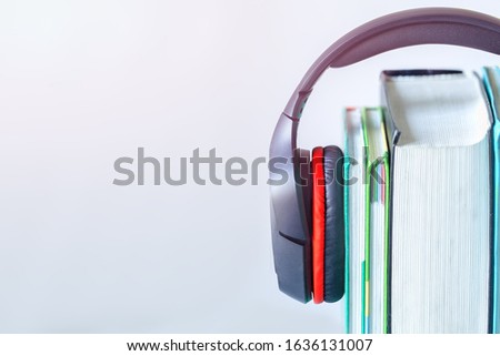 Modern headphones and books on table on white background. Concept of audiobook. Space for text.
