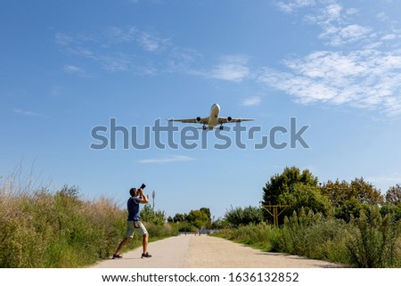 Photographer taking photo of an airplane landing. Focus selected. Spotting concept
