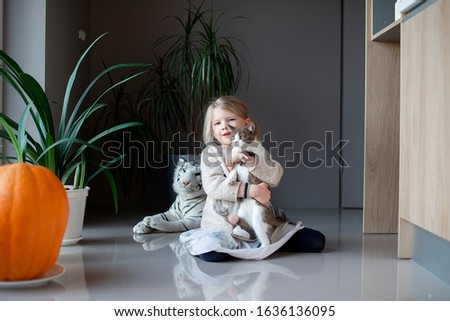 a little girl sits on the floor and holds a cat in her hands