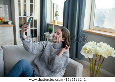 Flirting. Dark-haired girl in a grey sweater looking flirty