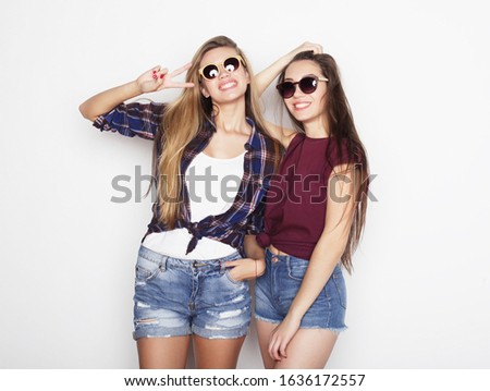 lifestyle, emotion and people concept: Two young girl friends standing together and having fun. Hipster style.