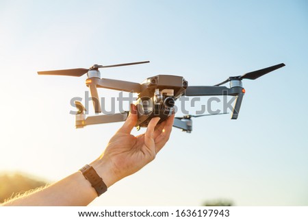 drone copter in hand on sky background. Remote controlled copter with digital camera in the hand. Closeup. New tool for aerial photo and video. Royalty-Free Stock Photo #1636197943
