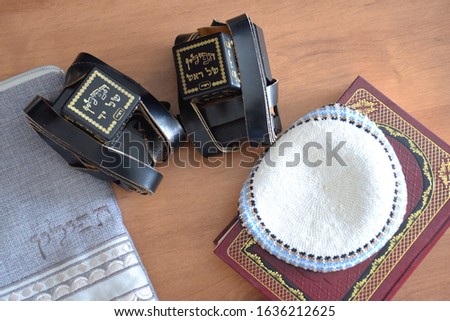 Black Tefillin (Judaica item using for the famous jewish prayer "Shema Israel" - hear us our lord, made from leather), the Jewish bible book and white 'Kippah' (skullcap) and a bag for the Tefillin. Royalty-Free Stock Photo #1636212625