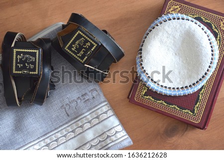 Black Tefillin (Judaica item using for the famous jewish prayer "Shema Israel" - hear us our lord, made from leather), the Jewish bible book and white 'Kippah' (skullcap) and a bag for the Tefillin. Royalty-Free Stock Photo #1636212628