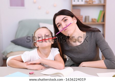 Mom helps the girl to do homework. Children and parents.
