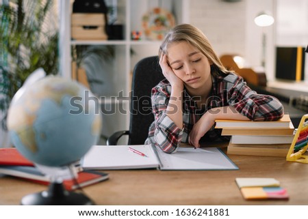 Back to school. Tired little child girl sleeping while doing homework with head on books.
Tired Teenager sleep on the Books.
Boring test in class room.