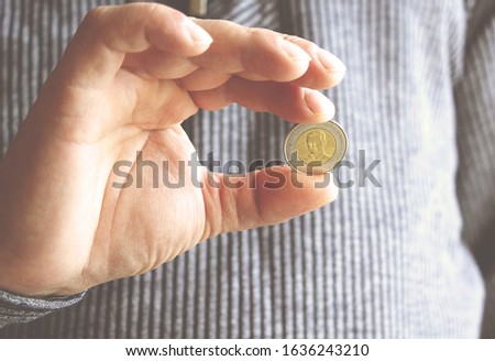 The Spanish coin lies on a male hand. The game "Eagle or Tails".