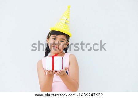Little girl holding gift box standing over white background,copy space.