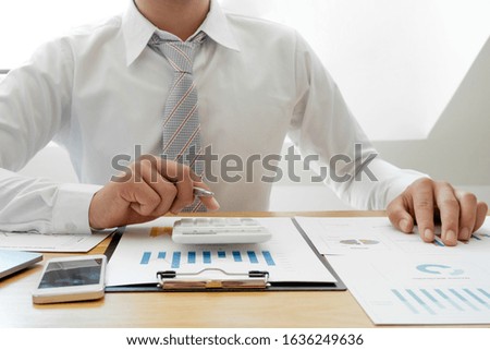 A business man is sitting at a desk and calculating financial graphs about real estate investment expenditures.