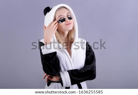 Young woman with patches in panda bathrobe. Beauty concept.