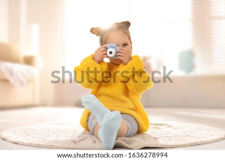 Little photographer taking picture with toy camera at home
