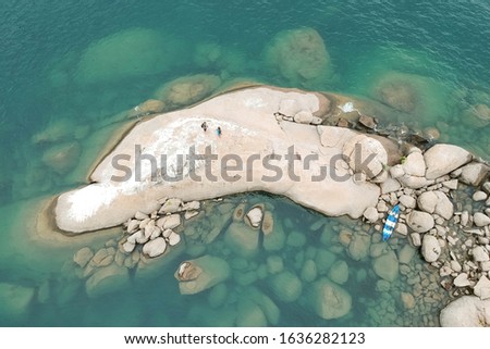 top view drone shot of a stoney cliff of a coastline with two people and a boat in Monkey Bay, Lake Malawi, Malawi
