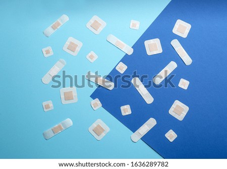 Different types of sticking plasters on blue background, flat lay