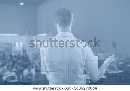 Speaker in meeting at business conference event. Seminar audience blurred in training room watch presentation. Presenter giving talk to people. City landscape double exposure.
