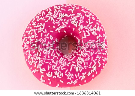 Pink donut with icing on pastel pink background.
