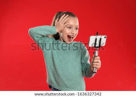 Excited little blogger recording video on red background