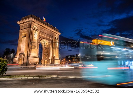 Arch of Triumph (Arcul de Triumf), Triumph Arch in Bucharest, Romania. Evening with beautiful sky above Bucharest, with a bus departing from the station in front of the Triumphal Arch. Motion effect. Royalty-Free Stock Photo #1636342582