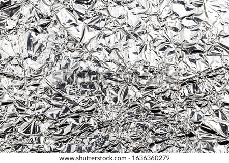 Texture of crumpled aluminum kitchen foil. Silver abstract background for design.