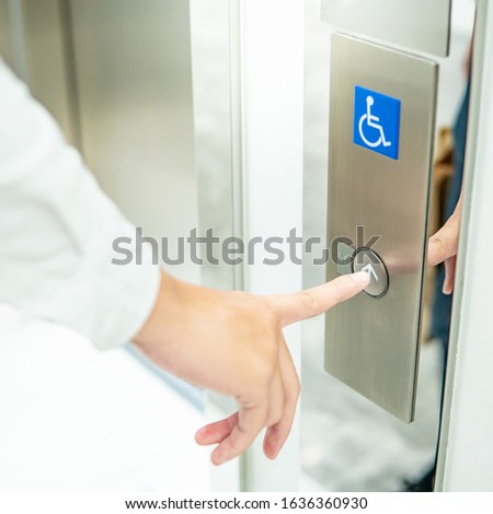 Male forefinger pressing on up button of elevator for blind or disability people (disabled lift). Handicap lift for hospital or medical center.