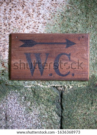 wood toilet sign on a stone wall