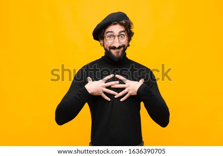 young french artist man looking happy, surprised, proud and excited, pointing to self against orange wall