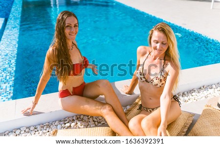 Beautiful girls having fun by the pool with wine and talking about travel and the weekend. Discuss March 8th. Holidays and parties by the pool in a villa by the sea. Thailand, Samui