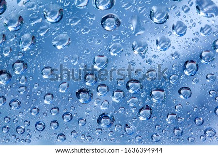 Backdrop glass covered with drops of water. Photo closeup with white and light blue background