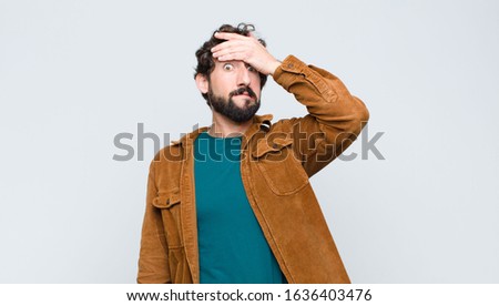 young handsome man panicking over a forgotten deadline, feeling stressed, having to cover up a mess or mistake against flat wall Royalty-Free Stock Photo #1636403476