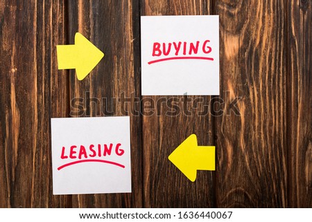 top view of papers with buying and leasing lettering on wooden surface
