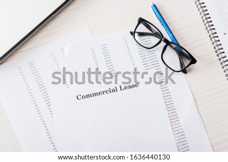 top view of document with commercial lease lettering near glasses on desk