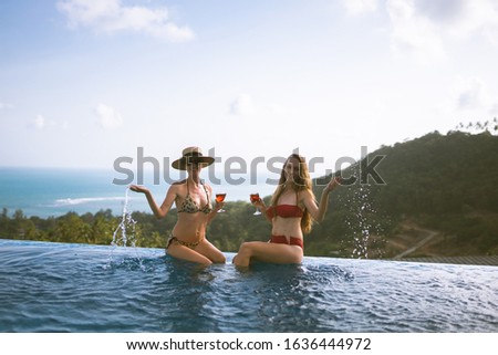 Beautiful girls having fun by the pool with wine and talking about travel and the weekend. Discuss March 8th. Holidays and parties by the pool in a villa by the sea. Thailand, Samui