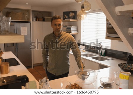 Portrait of handsome man standing in modern kitchen at home. Social distancing and self isolation in quarantine lockdown for Coronavirus Covid19
