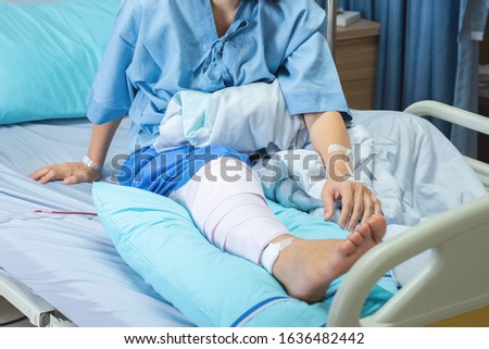 Asian senior or elderly old woman patient lying with bandage compression knee brace support injury on the bed in nursing ward hospital.