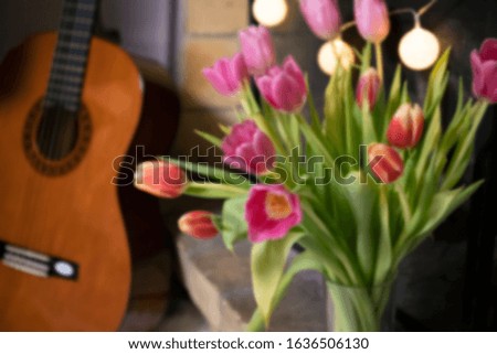 Pink and red tulips on a background of garlands of light bulbs, brick and guitars. Blurred photo close-up