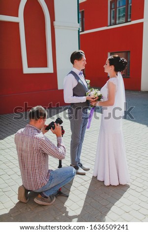 Photographer taking pictures of the bride and groom near the red building