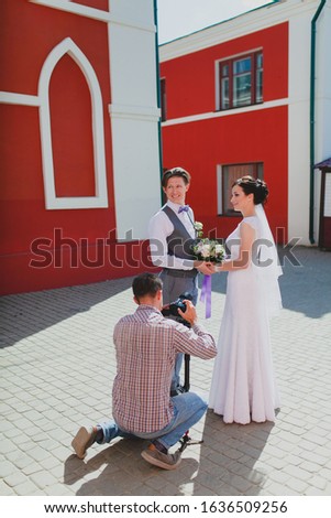 Photographer taking pictures of the bride and groom near the red building