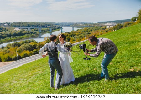 Wedding photographer taking pictures of the bride and groom on a hillside