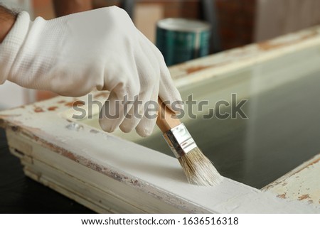 Repairman painting old window at table indoors, closeup Royalty-Free Stock Photo #1636516318