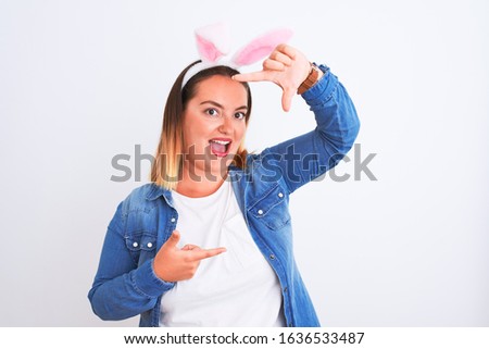 Young beautiful woman wearing banny ears standing over isolated white background smiling making frame with hands and fingers with happy face. Creativity and photography concept.