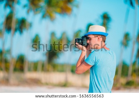 Young man photographed at camera on tropical beach