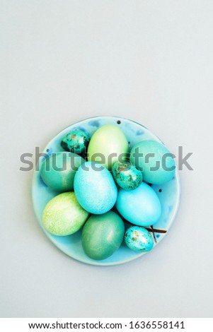 Bright multi-colored Easter eggs in a plate on a gray background, top view. Easter background.	

