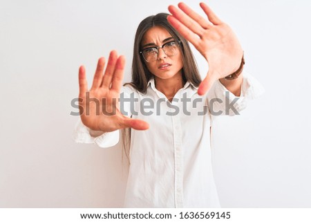 Young beautiful businesswoman wearing glasses standing over isolated white background doing frame using hands palms and fingers, camera perspective