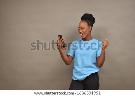 beautiful young african lady using her mobile phone feeling happy and excited
