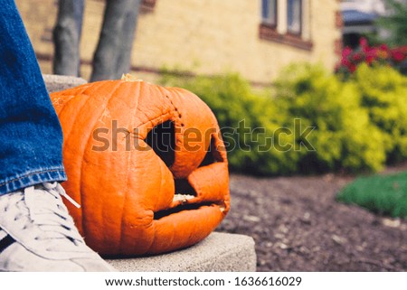 Smashed face pumpkin that has been sitting outside so long it has collapsed and sagged