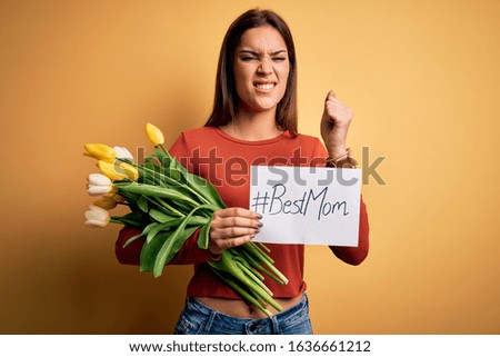 Beautiful woman celebrating mothers day holding best mom message and bouquet of tulips annoyed and frustrated shouting with anger, crazy and yelling with raised hand, anger concept