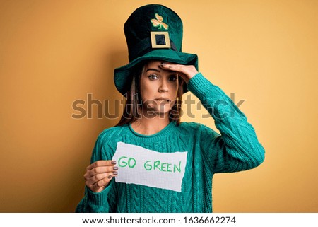 Young beautiful woman wearing green hat celebrating saint patricks day holding message stressed with hand on head, shocked with shame and surprise face, angry and frustrated. Fear and upset 