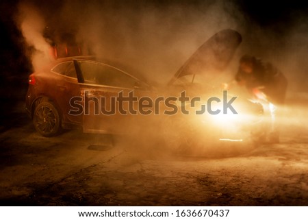 Car that was on fire at night with fire fighter lights in background
