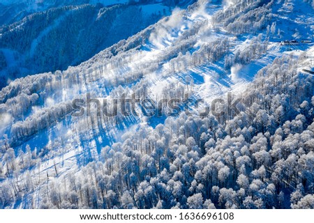 Winter Mountain landscape at the Rosa Khutor ski resort in Sochi, Russia. Trees in hoarfrost against a beautiful morning sky in a frosty morning. Snow cannons sprinkle snow on the slopes